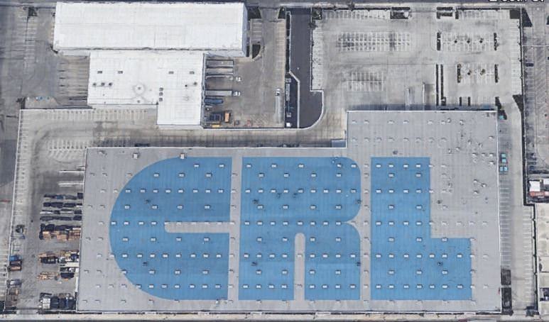 A parking lot full of cars that is next to a building with the letters CRL printed on the white roof