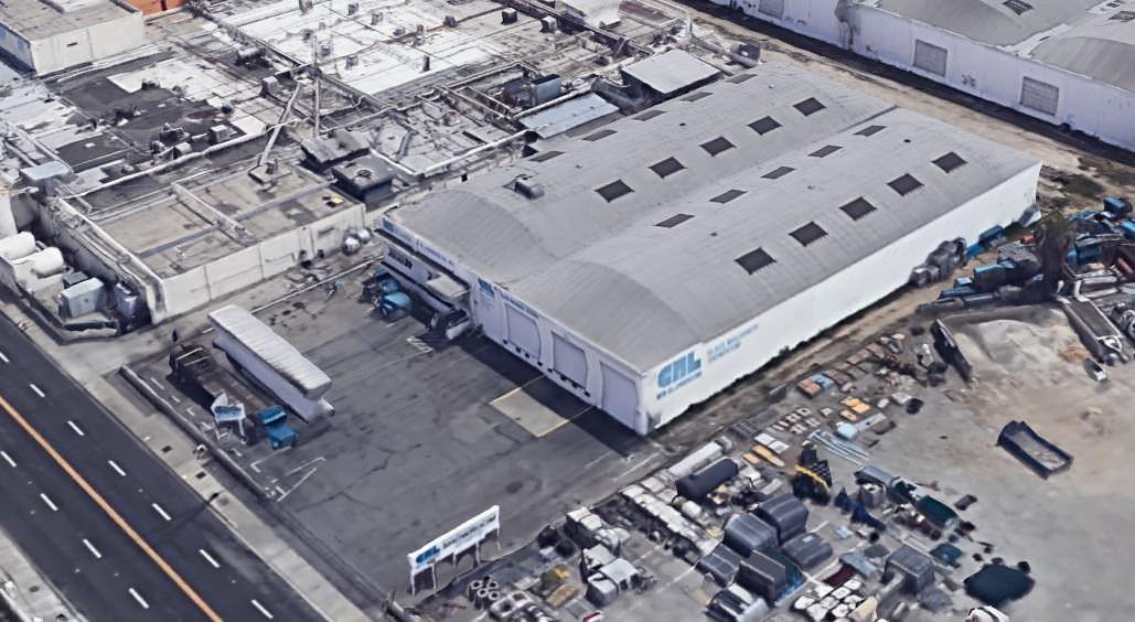 An aerial view of a warehouse that has a lot of cars and vehicles around the front of it.