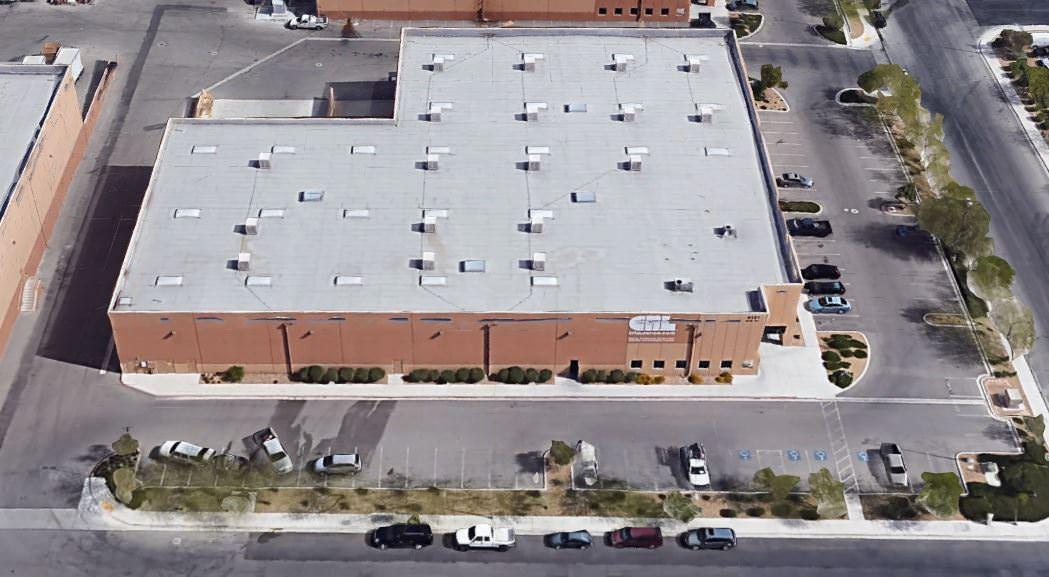An aerial view of a large retail store that has a big parking lot around the front and side of it.