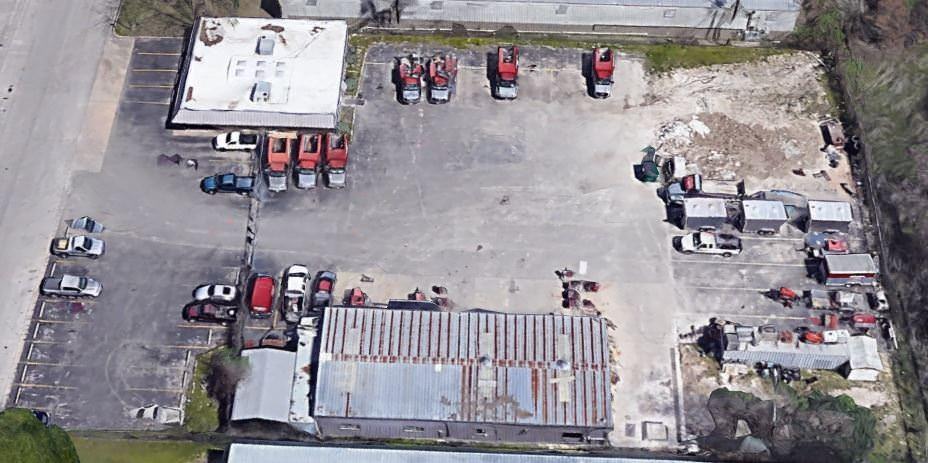 A group of small buildings that is surrounded by a parking lot full of cars and trucks.