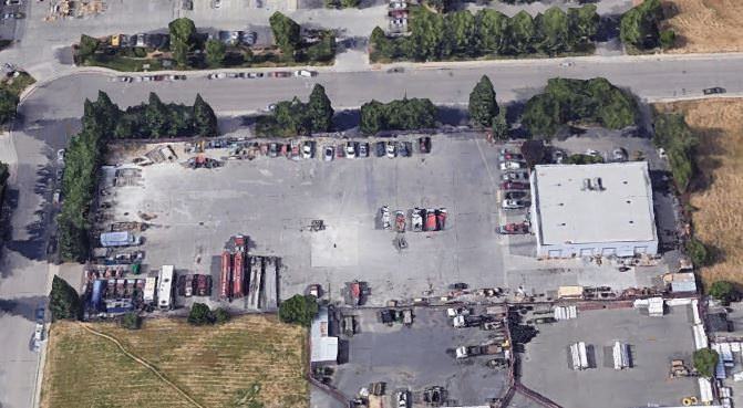 Cars that are parked in a parking lot as viewed from the air near a small building.
