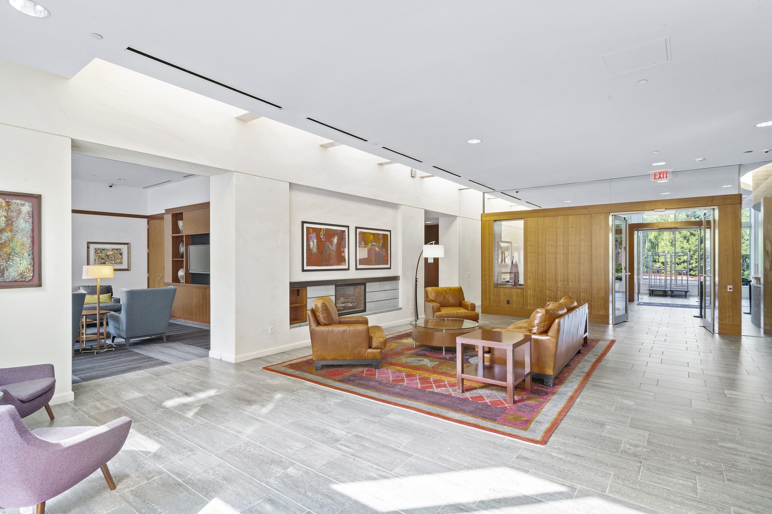 An empty lobby of a building that is full of furniture with a set of glass doors.