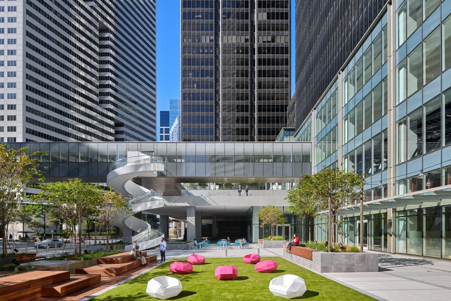 Render of the exterior of the building with a large outdoor lawn that has pink and white chairs.