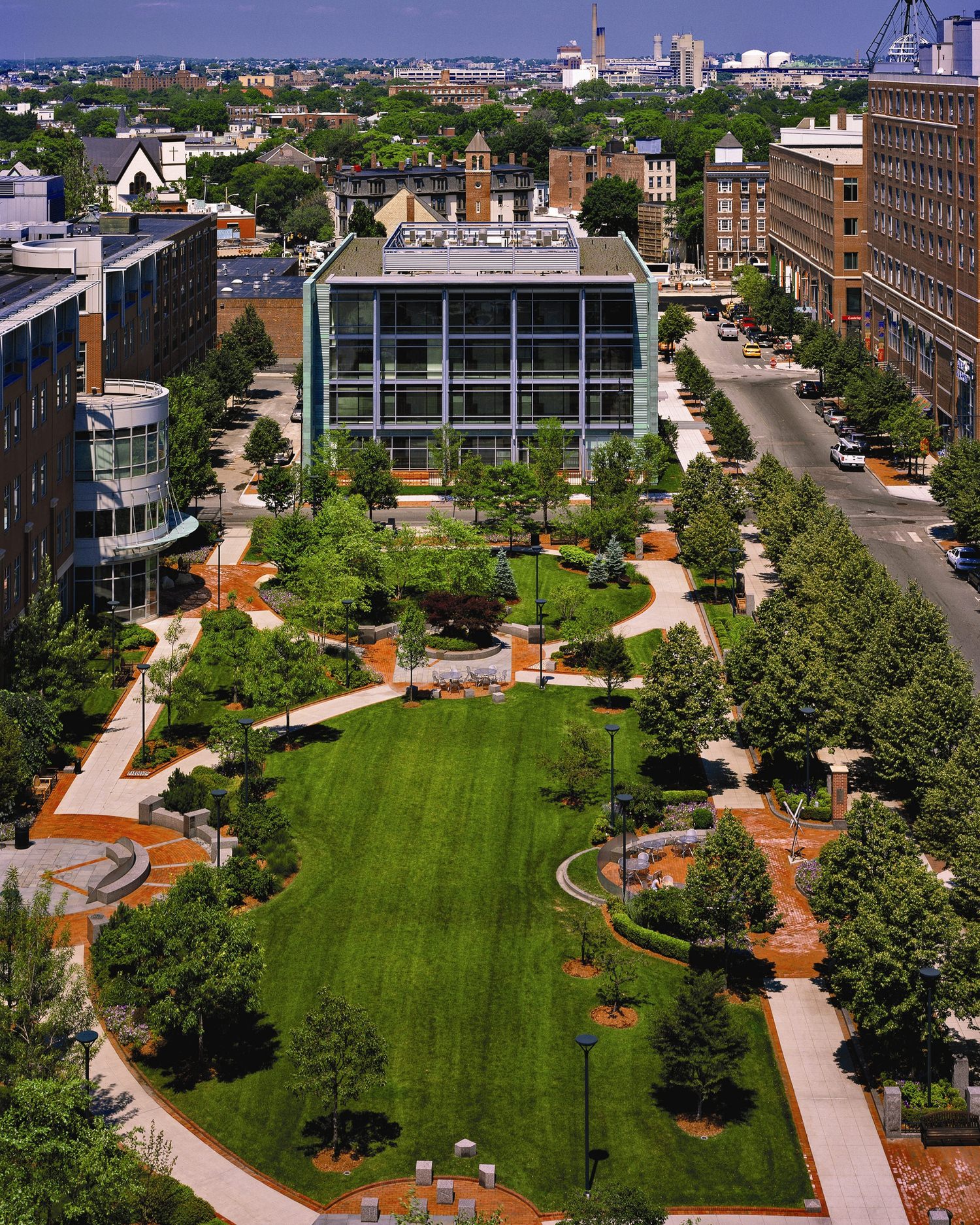 A large courtyard full of grass and trees lining the sides of the walkways towards the buildings.