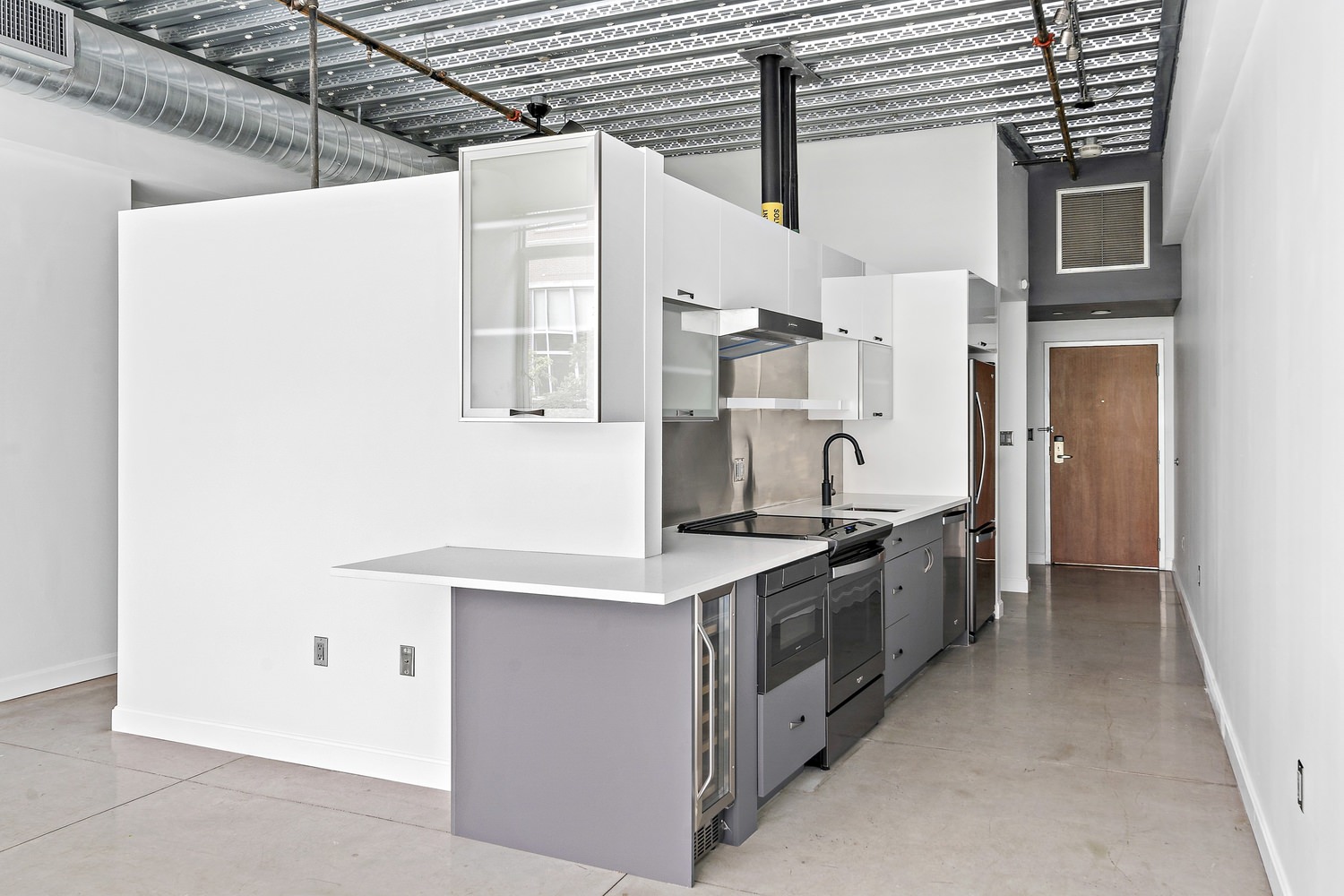 Kitchen and living room area of an apartment that has white walls and tiled floors.