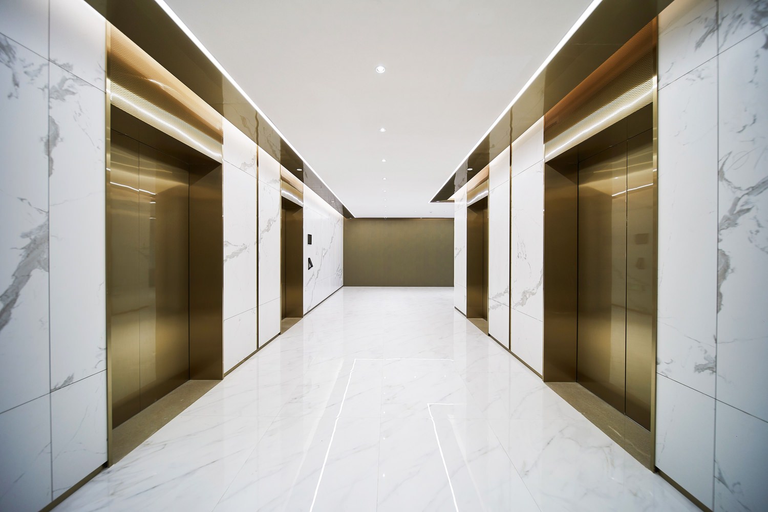 One EaThe inside of a building that has a hallway with elevators on either side of it and tile floors.st – Tower C