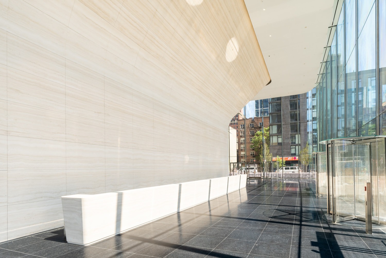 Outdoor image of a glass building where the floor are installed with white cube tiles