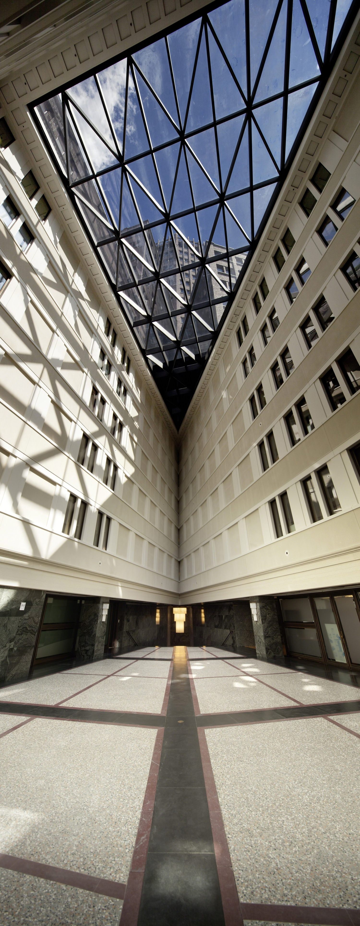 A courtyard inside of a building that has a glass skylight on the top of it and windows.
