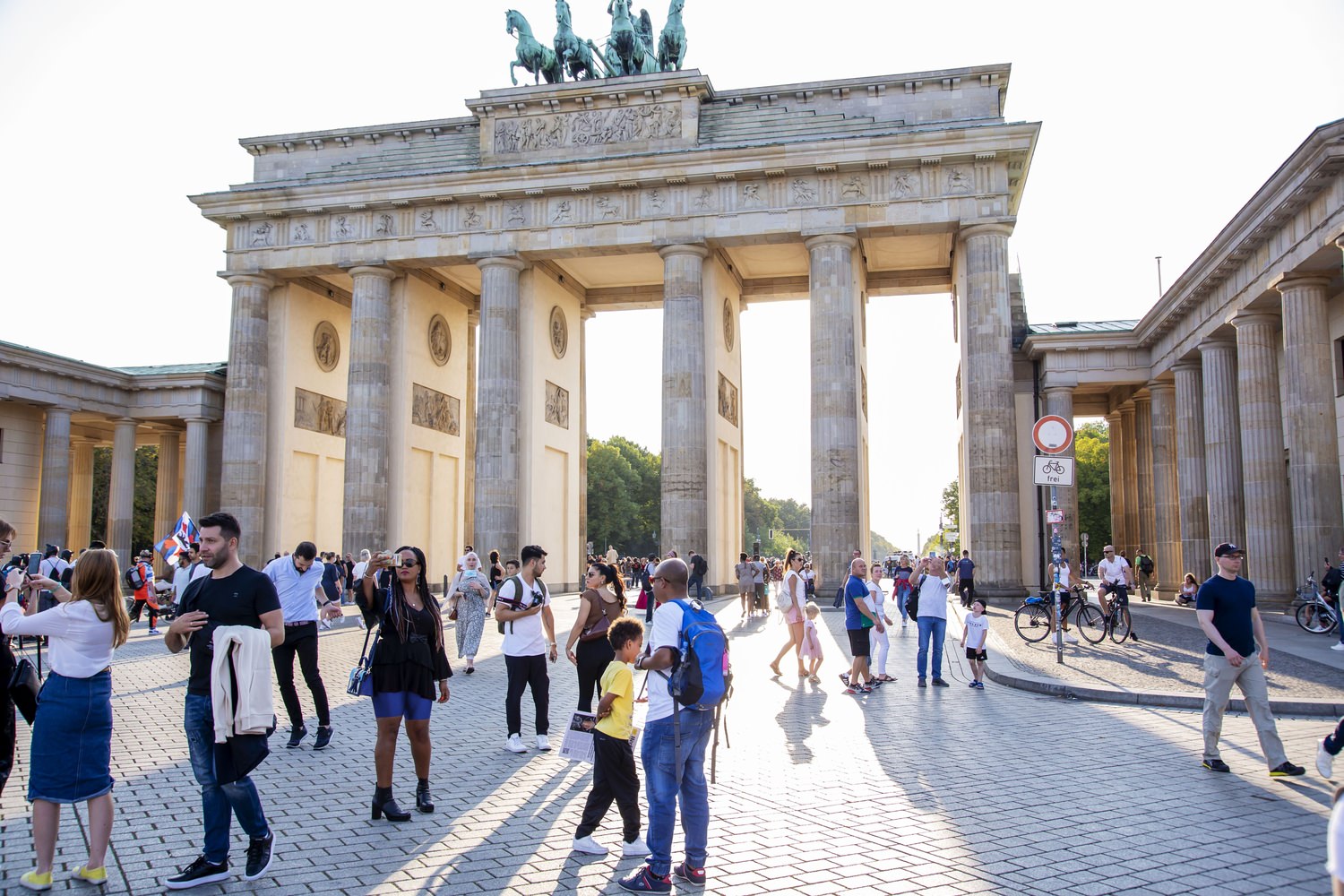 A large group of people that are standing in front of the Brandenburg Gate in Germany while taking photos.