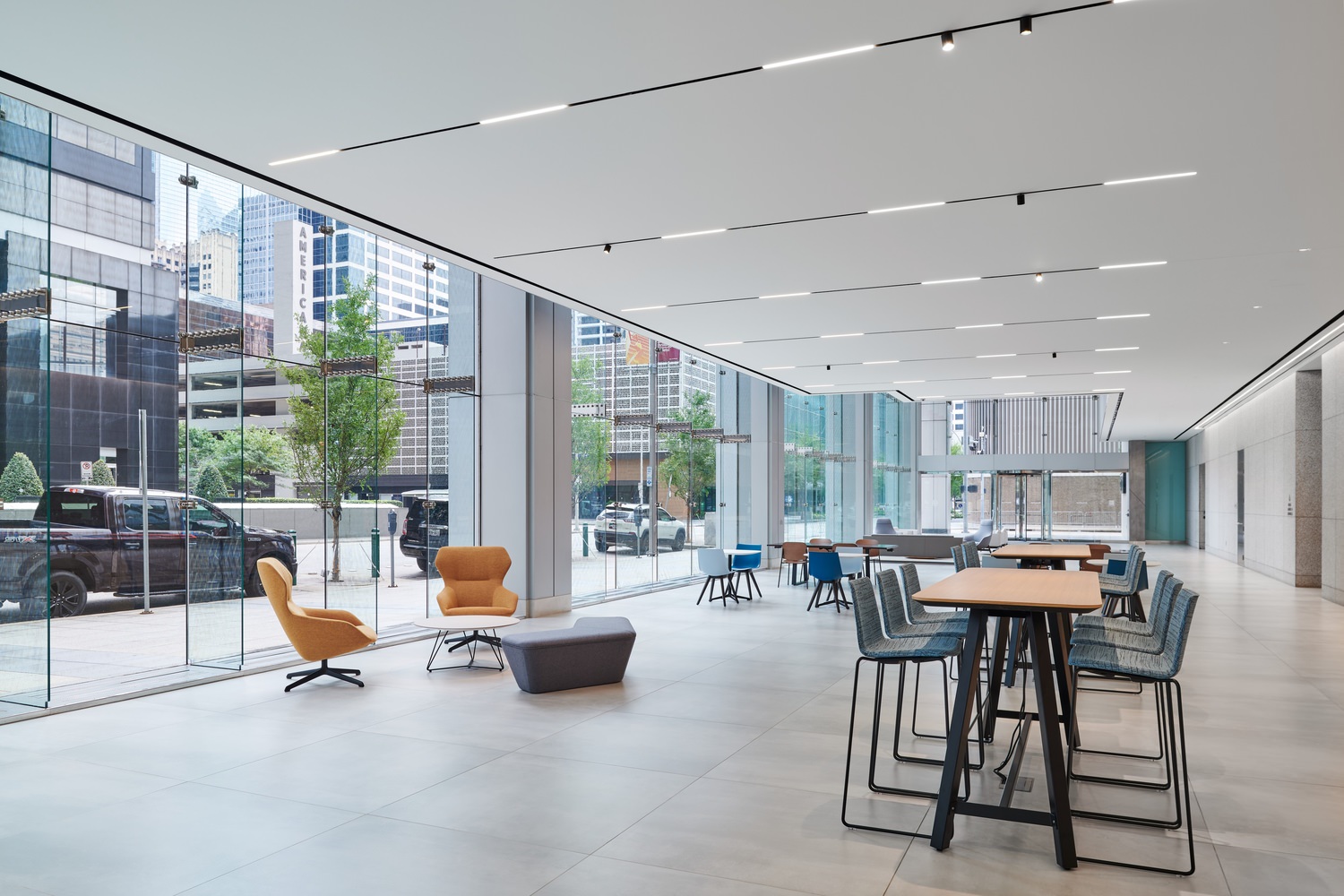 The lobby of a large building that has some high tables with chairs and seating areas.