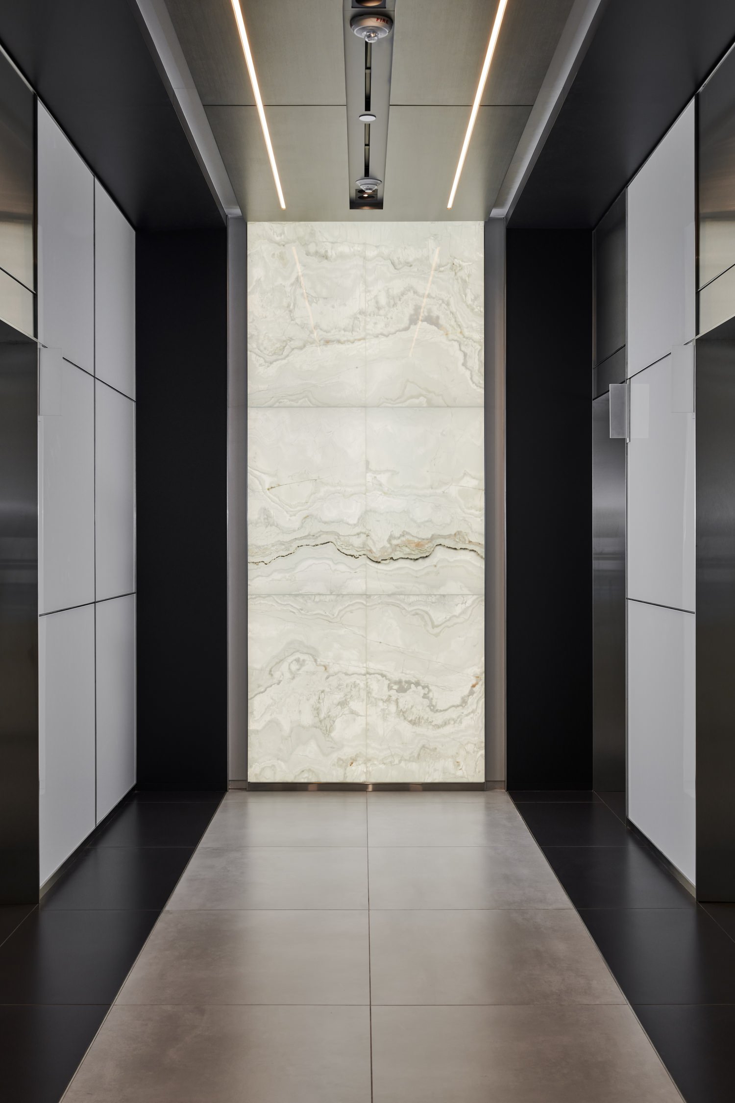 Indoor hallway with walls and floors that full of rows of black and white tiles.