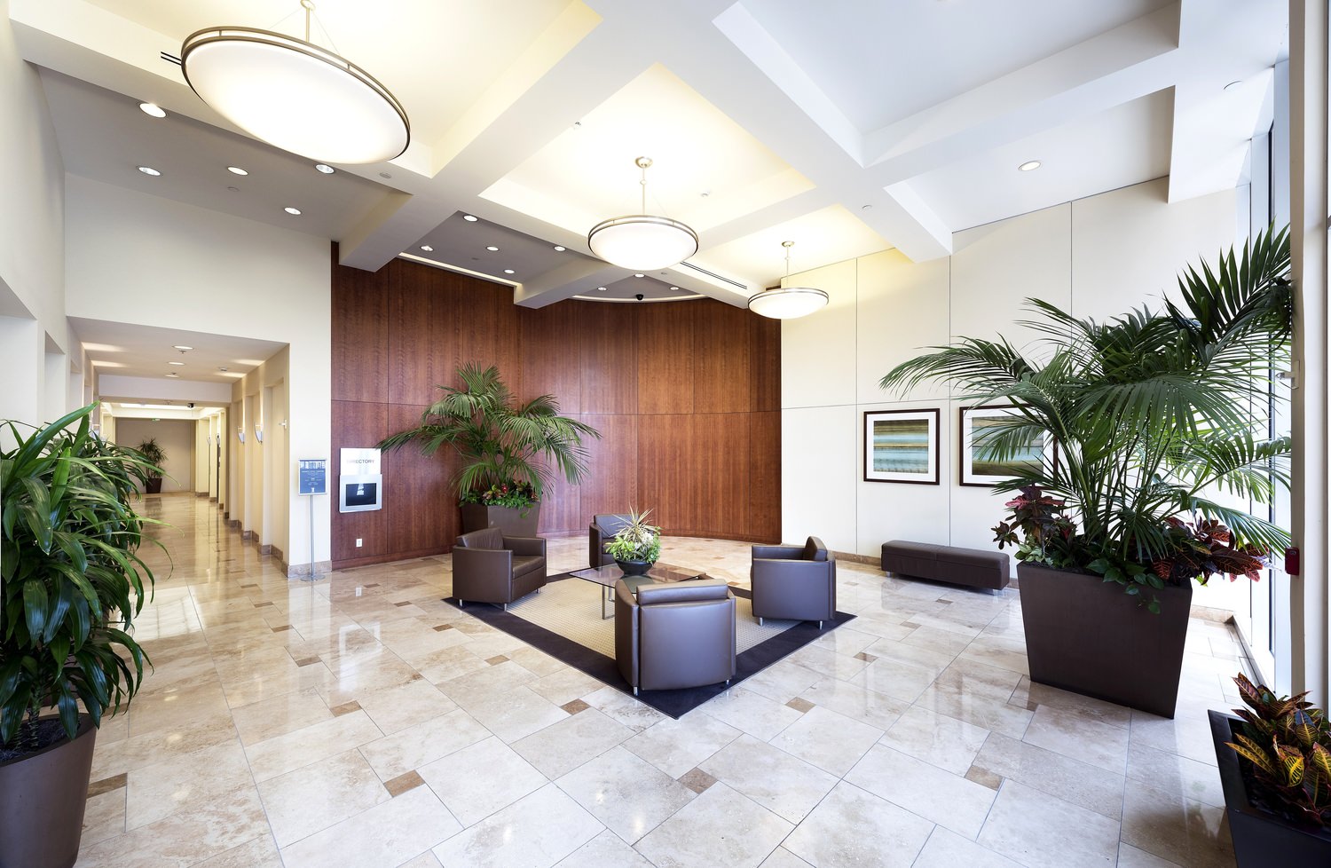 Indoor lobby of a building that has plants and different furnitures like couches.