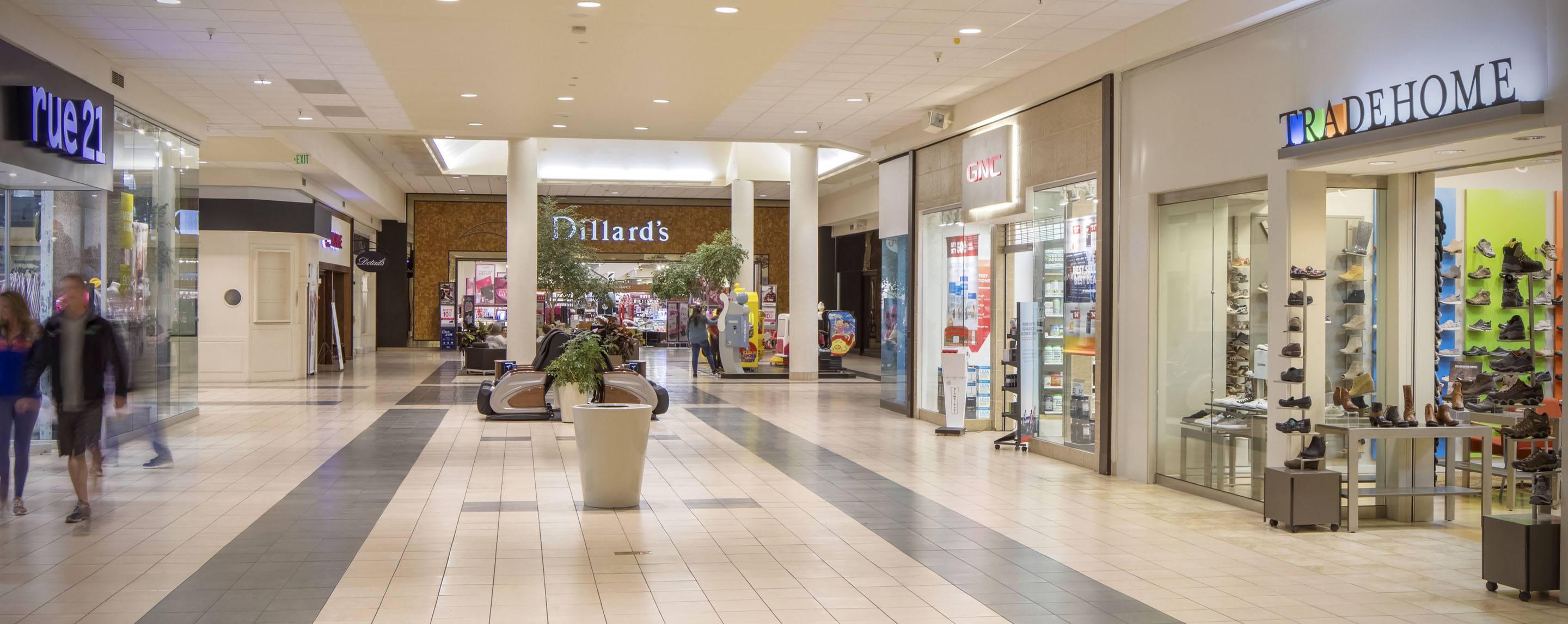 A Dillards store is situated next to a Trade Home store and a Rue 21 store inside of an indoor shopping mall.