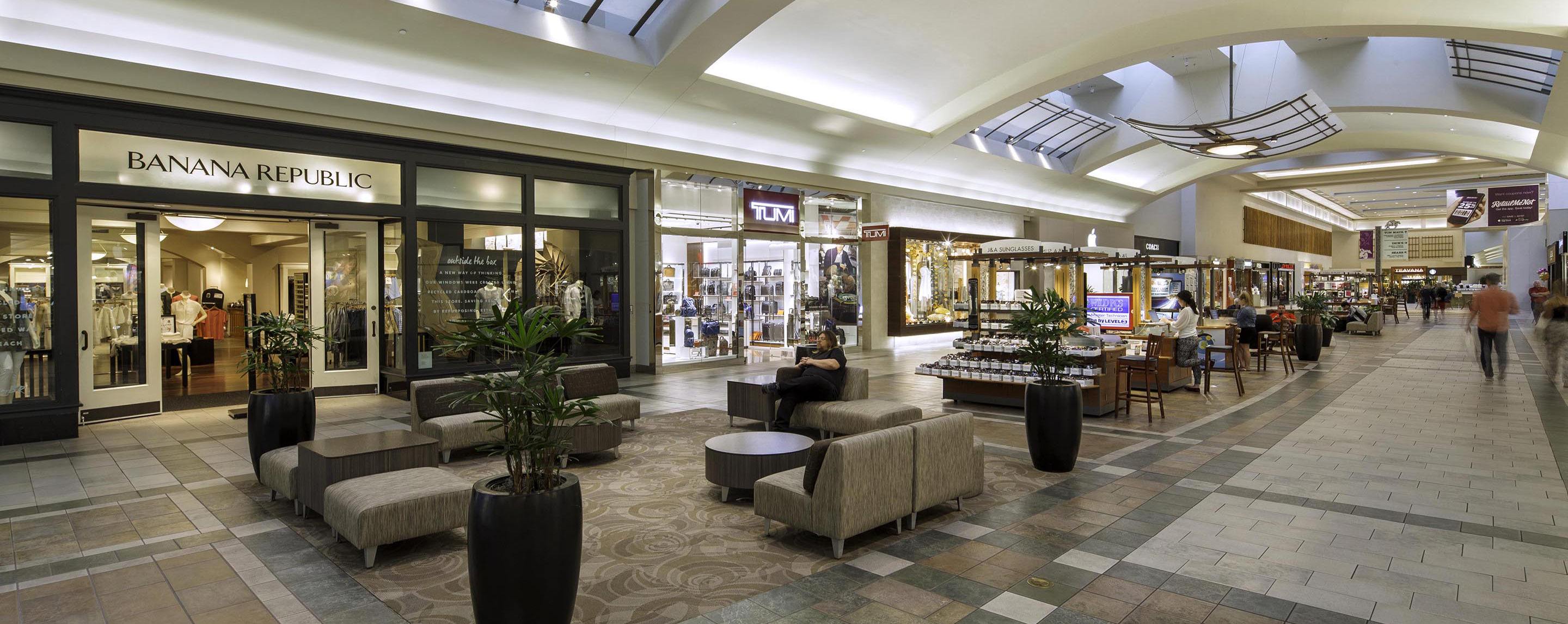 A view of an indoor mall. There are many storefronts, including Tumi, Coach, Von Maur, and Banana Republic.