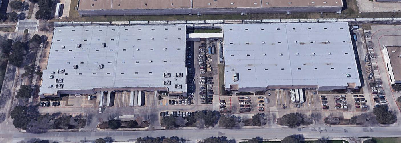 An aerial view of a building that has some semi trucks backed into the loading docks