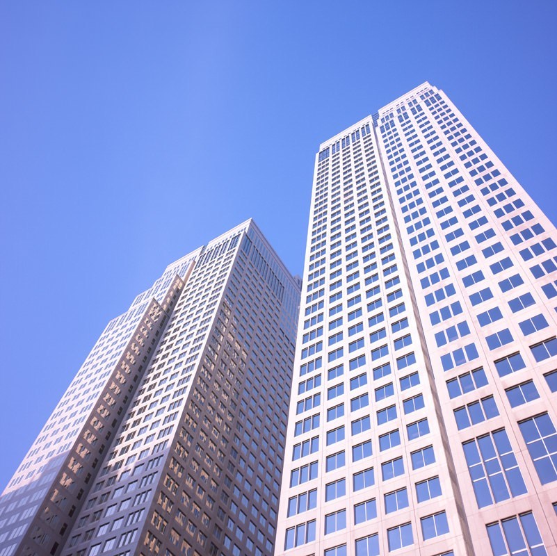 View looking up at two tall white skyscrapers from below.
