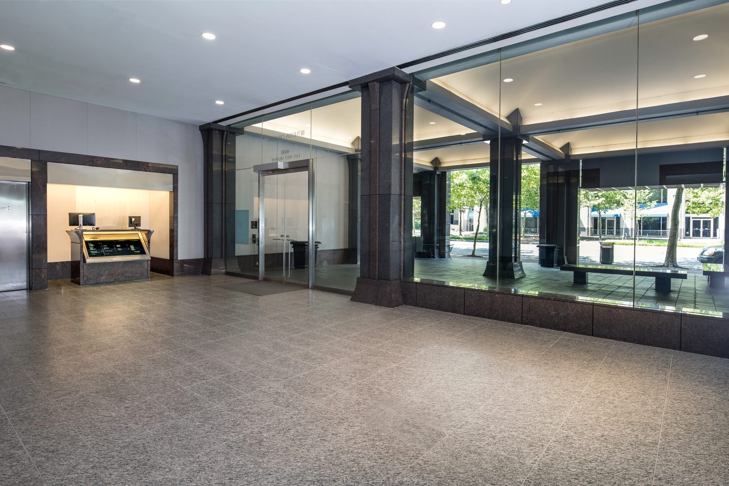 A lobby with dark gray tile and large glass windows.