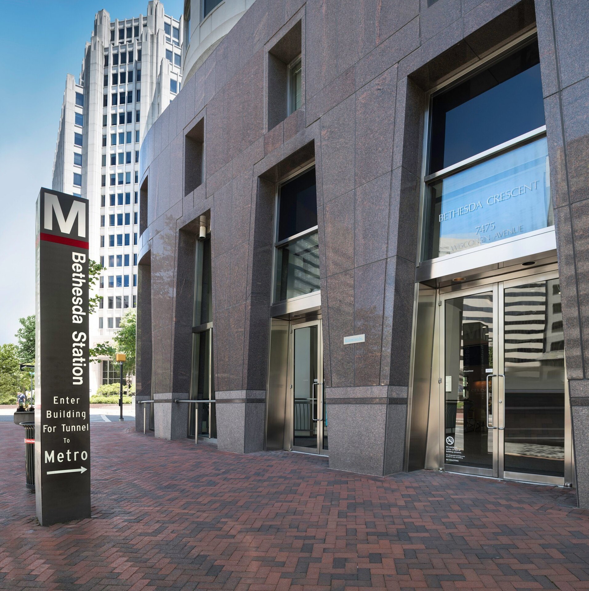 Entrance to a building with a sign that says "M Bethesda Station Enter Building for Tunnel to Metro". The sign has an arrow that points to the building.
