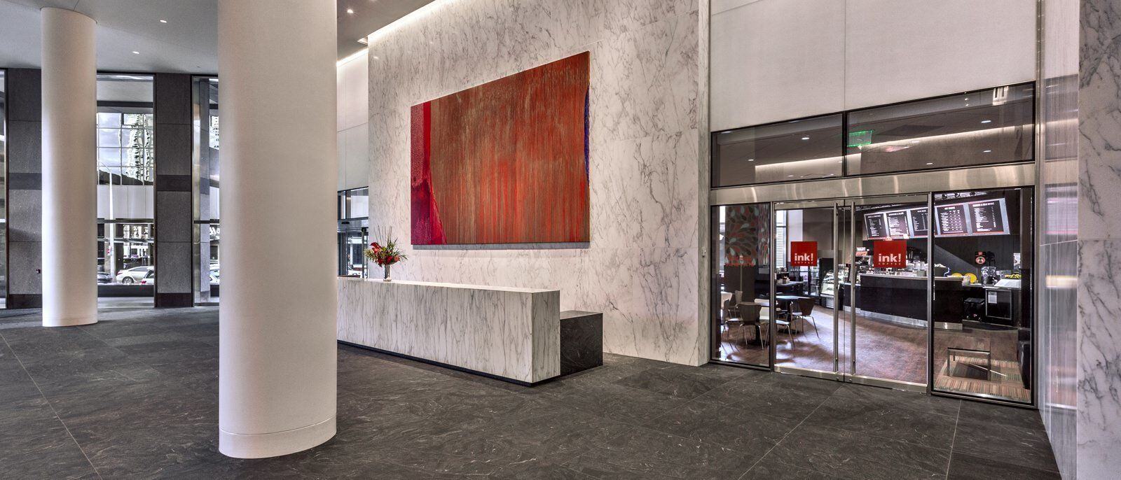 A marble lobby desk with a restaurant called Ink! behind it.