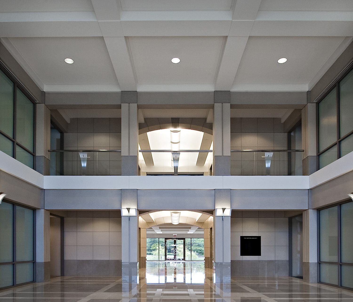 A view entering a building that has polished tile floors in it and a second floor looking over the entryway.