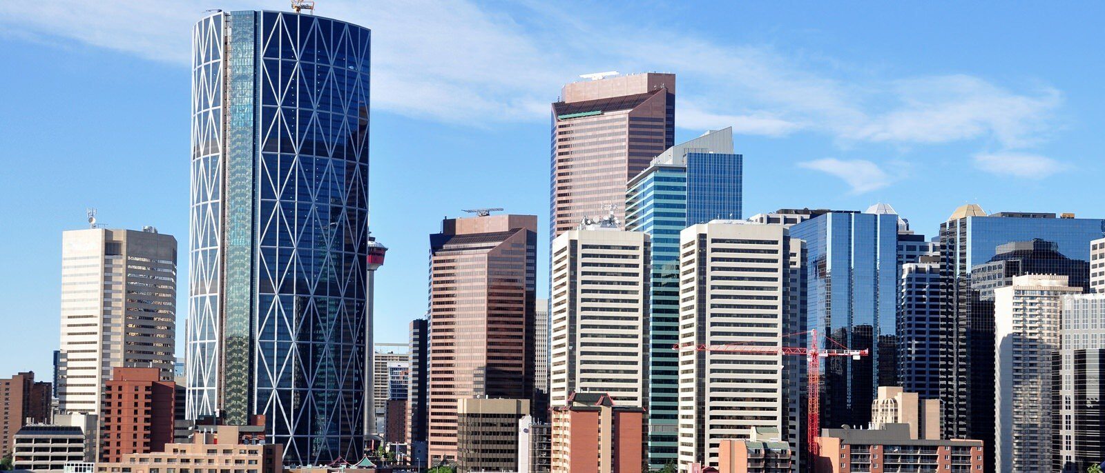 A view of a skyline in a large city that has some tall buildings and a red crane.